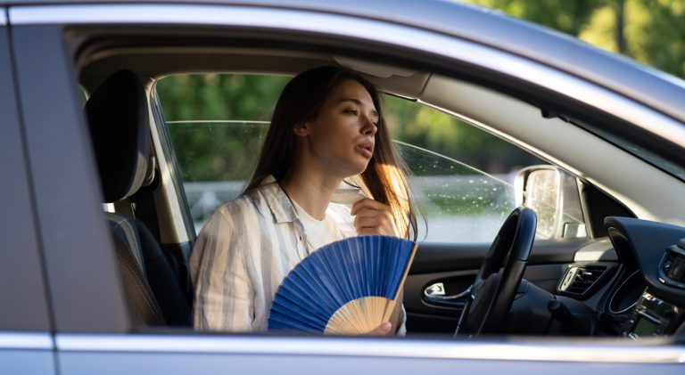 Exhausted,Young,Woman,Driver,With,Hand,Fan,Suffering,From,Heat